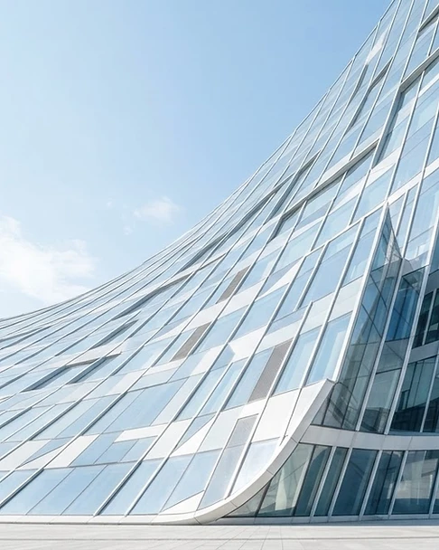 Curved glass facade reflecting daylight in geometric patterns